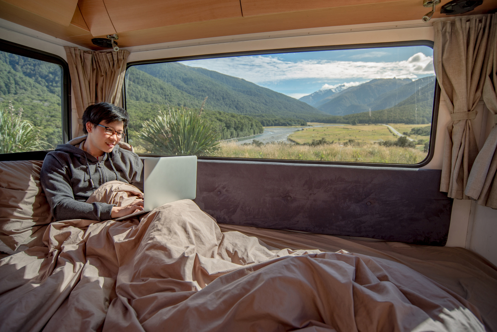 Young Asian man working with laptop in camper van